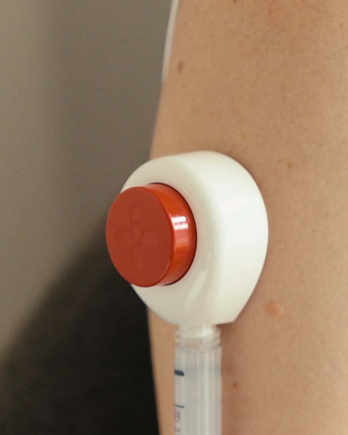 Gros plan sur le bouton rouge de démarrage d'un dispositif Tasso+ posé sur le haut du bras